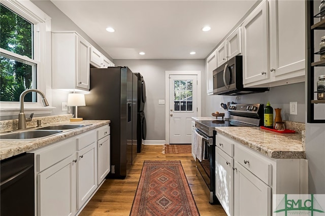kitchen featuring stacked washer and clothes dryer, light countertops, appliances with stainless steel finishes, and a sink