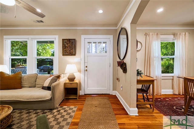 entryway featuring visible vents, light wood finished floors, baseboards, and ornamental molding