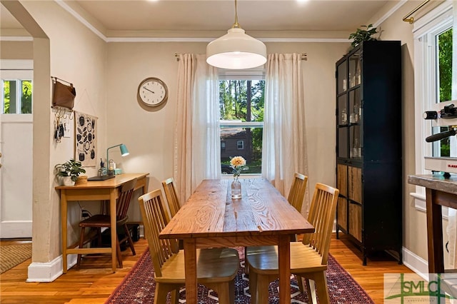 dining space featuring light wood finished floors, baseboards, and crown molding