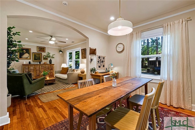 dining area featuring a ceiling fan, arched walkways, hardwood / wood-style flooring, and crown molding