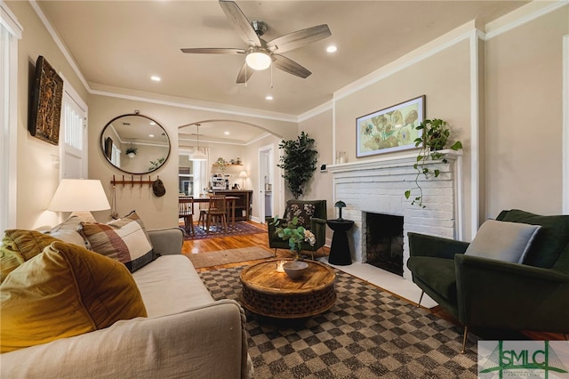 living room with a ceiling fan, wood finished floors, arched walkways, a fireplace, and recessed lighting
