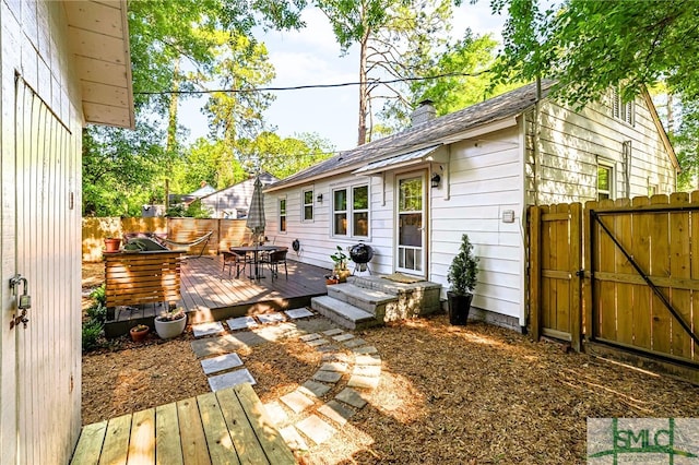 exterior space featuring a gate, a chimney, fence, and a deck