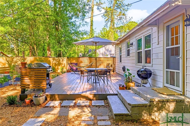 deck with a fenced backyard, outdoor dining area, and a grill