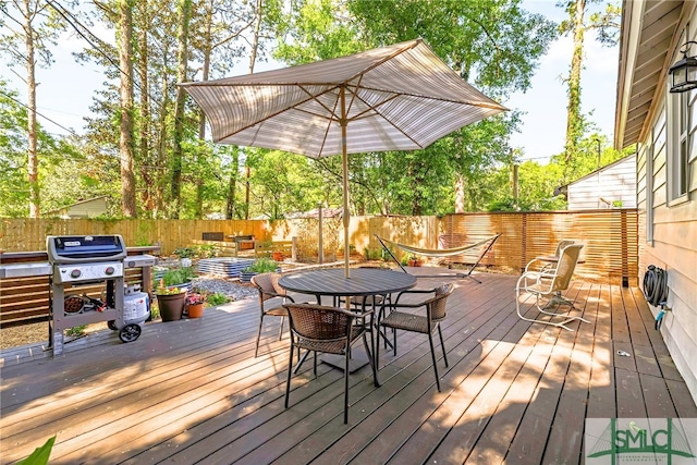 deck with area for grilling, a fenced backyard, and outdoor dining space