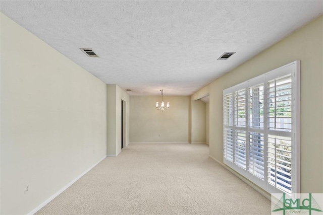 unfurnished room featuring carpet floors, a chandelier, visible vents, and baseboards