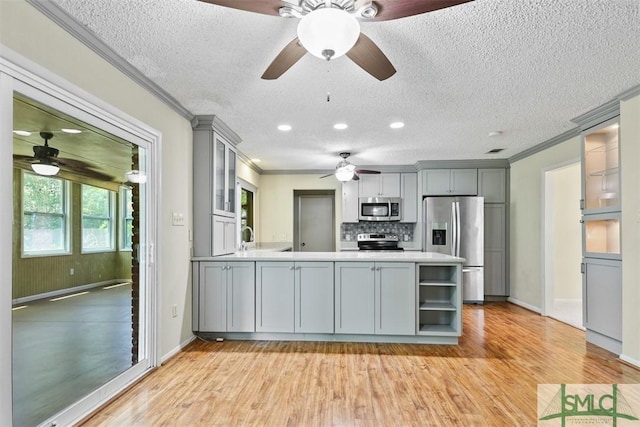 kitchen with crown molding, gray cabinetry, a peninsula, appliances with stainless steel finishes, and ceiling fan