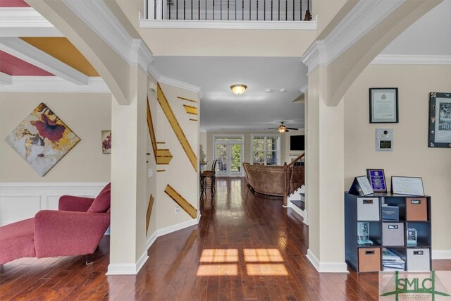 foyer featuring hardwood / wood-style floors, a ceiling fan, ornamental molding, arched walkways, and stairs