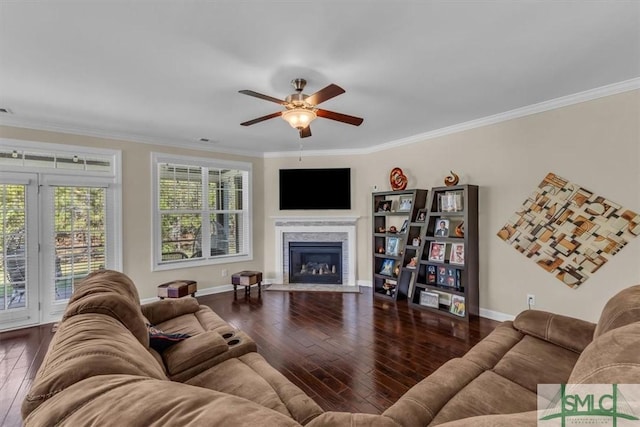 living room featuring crown molding, hardwood / wood-style flooring, a fireplace with flush hearth, ceiling fan, and baseboards