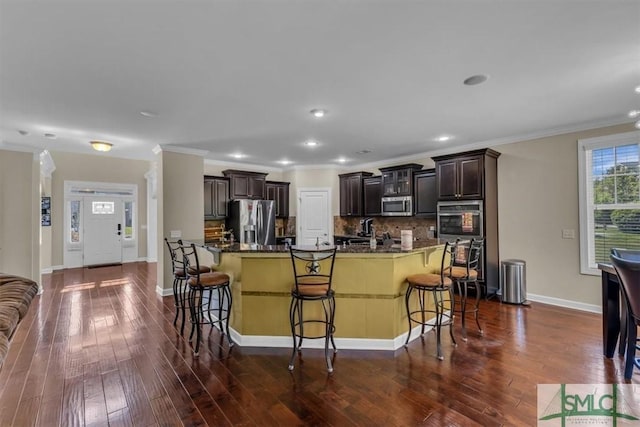kitchen featuring dark brown cabinets, stainless steel appliances, and a breakfast bar area