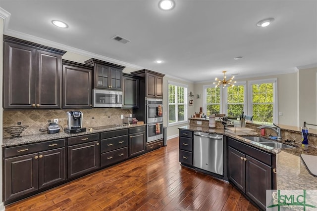kitchen with crown molding, a sink, dark wood finished floors, appliances with stainless steel finishes, and visible vents