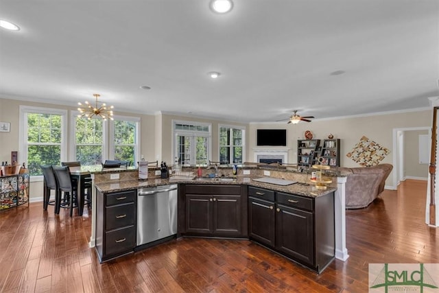 kitchen with dishwasher, a sink, crown molding, a fireplace, and open floor plan