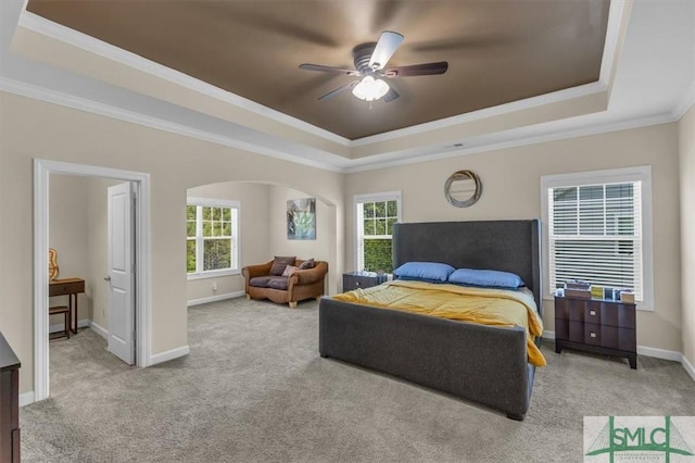 bedroom with arched walkways, ornamental molding, carpet floors, and a raised ceiling