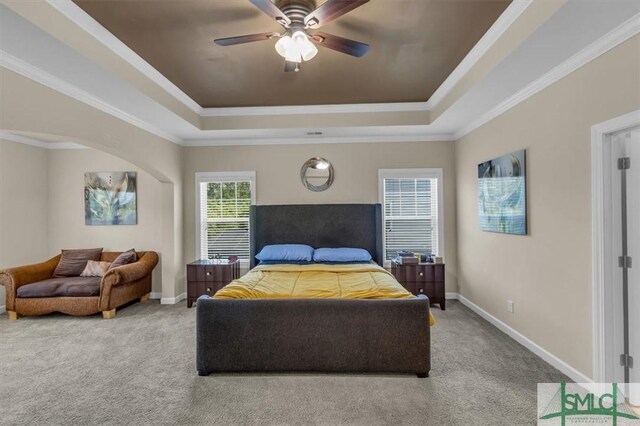 bedroom with a ceiling fan, a tray ceiling, baseboards, ornamental molding, and carpet flooring