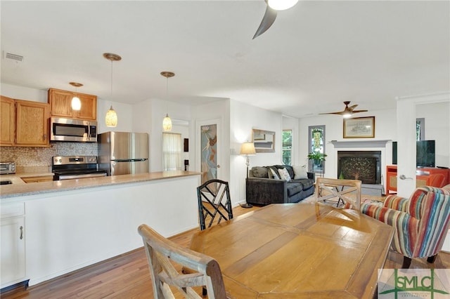 12 Carpenter Rd, Tybee Island, GA 31328 - dining area featuring a ceiling fan, light wood-type flooring, and a fireplace with raised hearth