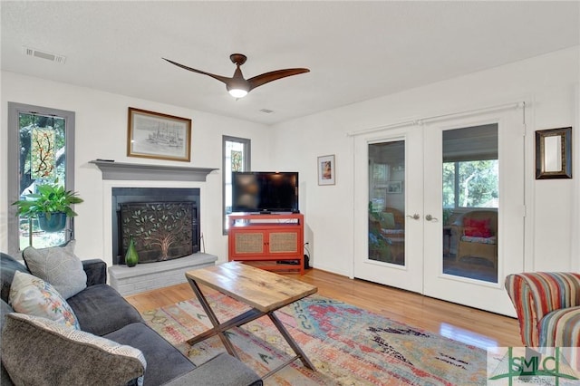 12 Carpenter Rd, Tybee Island, GA 31328 - living area with french doors, wood finished floors, a ceiling fan, and a fireplace with raised hearth