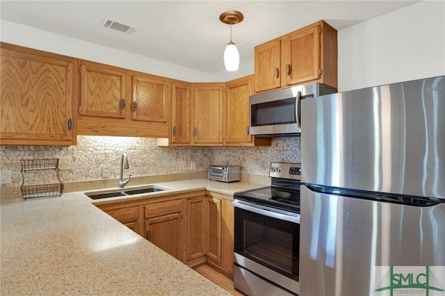 12 Carpenter Rd, Tybee Island, GA 31328 - kitchen featuring stainless steel appliances, light countertops, decorative backsplash, hanging light fixtures, and brown cabinetry