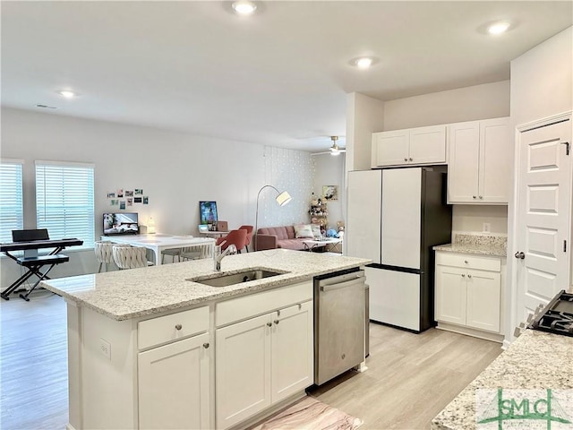 kitchen with dishwasher, a sink, white cabinets, freestanding refrigerator, and light wood-style floors
