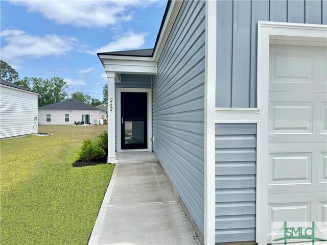 property entrance with a lawn and a garage