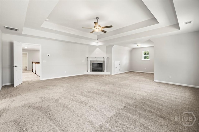 31 Oakmont Dr, Guyton, GA 31312 - unfurnished living room with a tray ceiling, a ceiling fan, carpet, and a glass covered fireplace