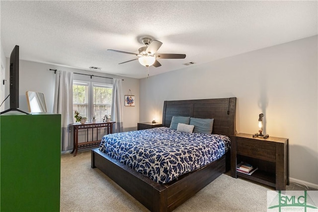 bedroom featuring light carpet, a ceiling fan, visible vents, and a textured ceiling