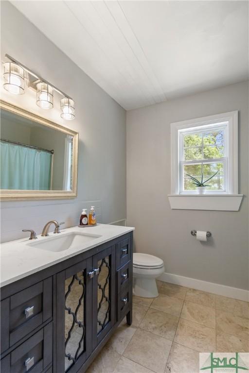 bathroom with baseboards, toilet, and vanity