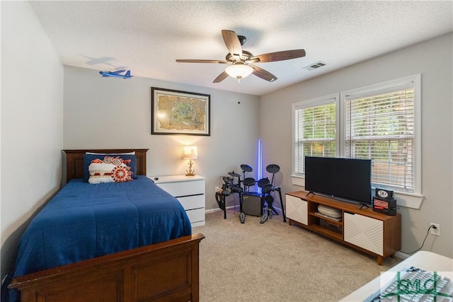 bedroom featuring a textured ceiling, visible vents, a ceiling fan, and light carpet