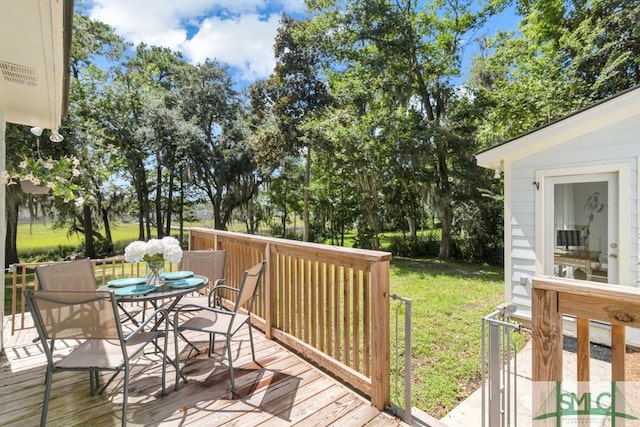 wooden deck featuring a lawn and outdoor dining space