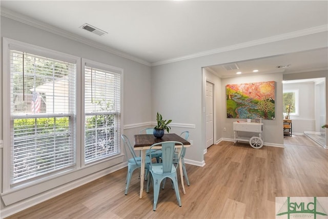 dining area with light wood-style floors, visible vents, crown molding, and baseboards