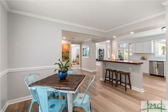 dining space with recessed lighting, light wood-style floors, crown molding, and baseboards