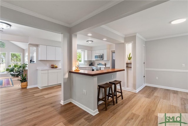 kitchen with light wood-style floors, white cabinetry, a breakfast bar area, and stainless steel appliances