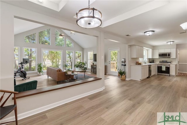 living room featuring light wood-style floors, lofted ceiling, baseboards, and ceiling fan with notable chandelier
