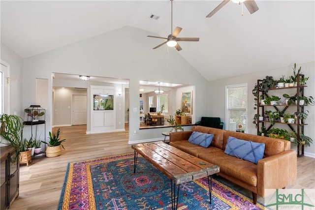 living room featuring light wood-type flooring, visible vents, a ceiling fan, and high vaulted ceiling