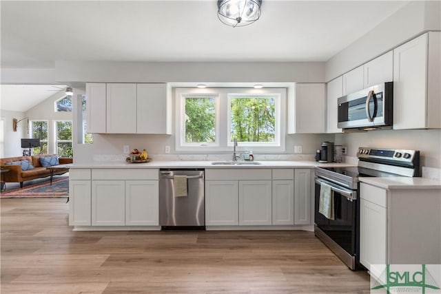 kitchen with light countertops, a sink, light wood-style floors, appliances with stainless steel finishes, and white cabinetry