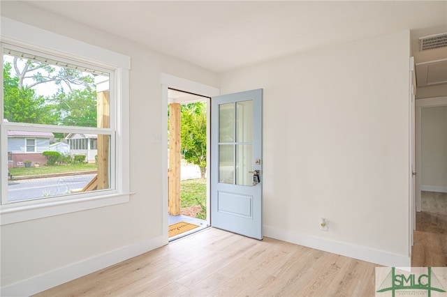 foyer entrance with baseboards, wood finished floors, and visible vents