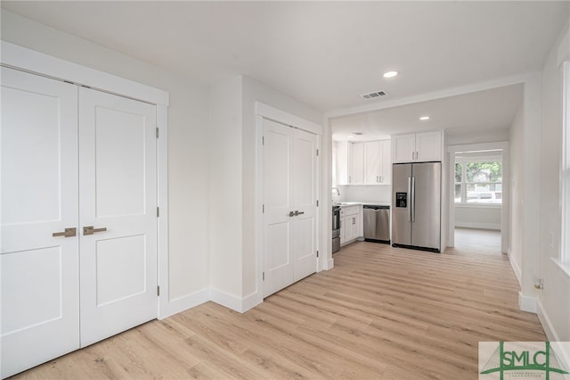 kitchen with baseboards, stainless steel appliances, visible vents, and light wood-style floors