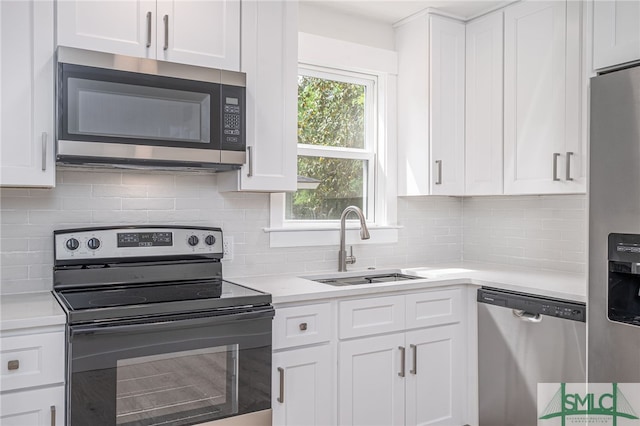kitchen with tasteful backsplash, a sink, light countertops, white cabinets, and appliances with stainless steel finishes