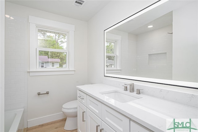 bathroom with wood finished floors, vanity, baseboards, toilet, and visible vents