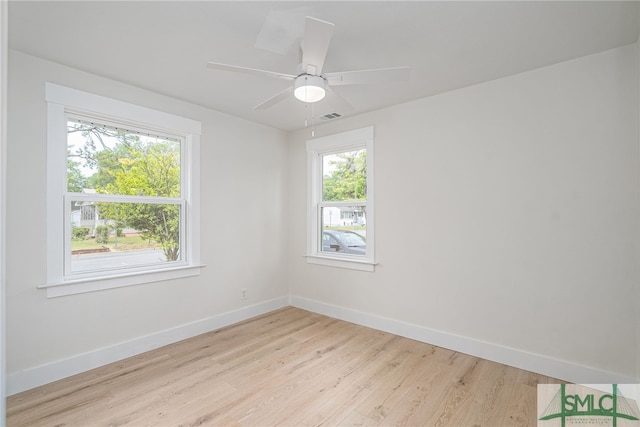 spare room with light wood-type flooring, a healthy amount of sunlight, baseboards, and visible vents