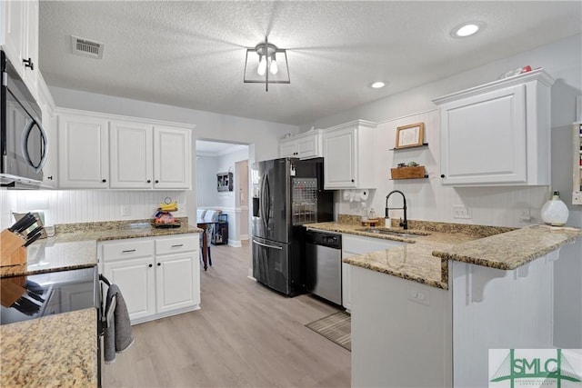 kitchen with a sink, black appliances, white cabinets, a peninsula, and visible vents