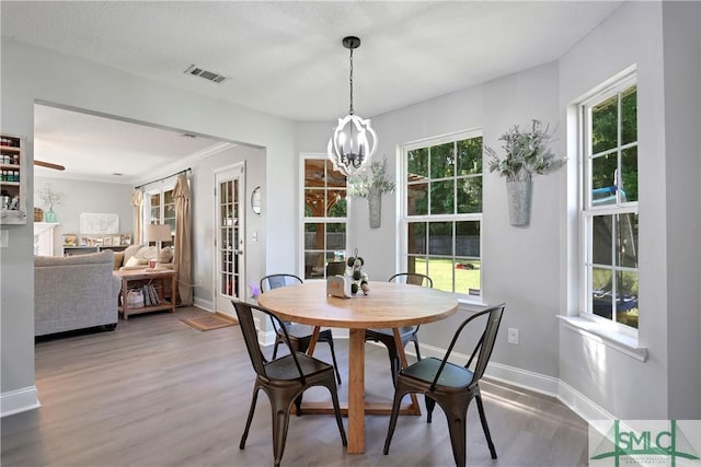 dining area featuring a chandelier, wood finished floors, visible vents, and baseboards