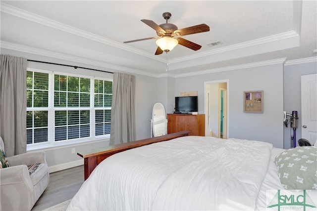 bedroom with wood finished floors, visible vents, crown molding, baseboards, and ceiling fan
