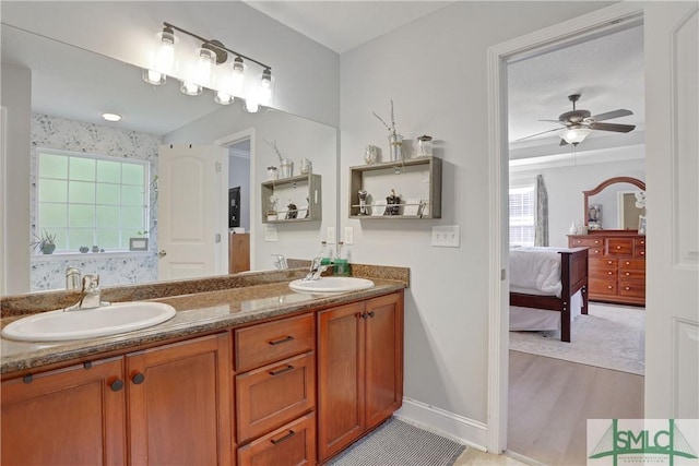 ensuite bathroom featuring ensuite bath, baseboards, ceiling fan, and a sink