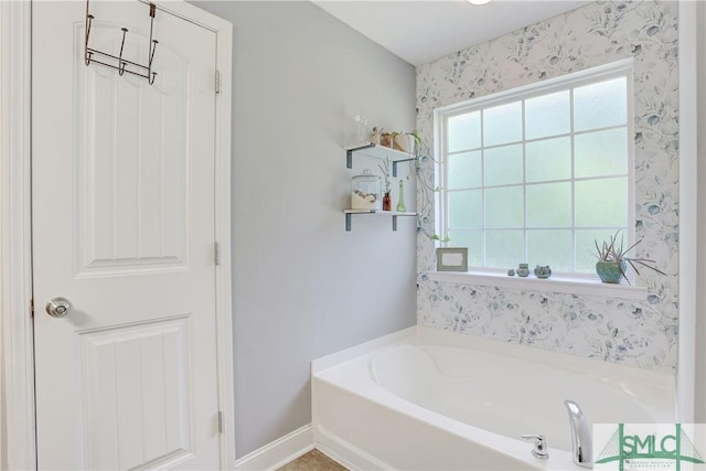 full bathroom with a bath, baseboards, and a healthy amount of sunlight