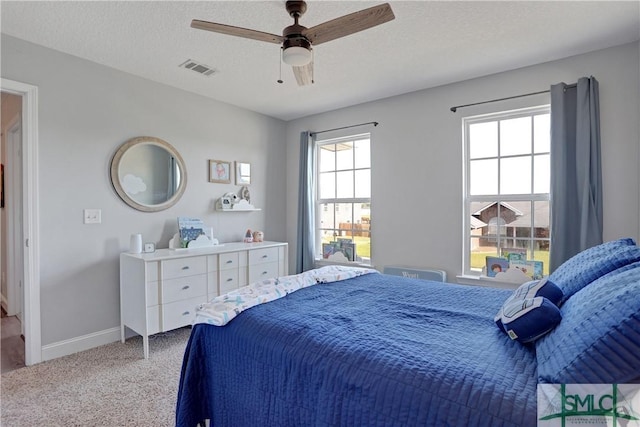 bedroom with a ceiling fan, a textured ceiling, baseboards, carpet flooring, and visible vents