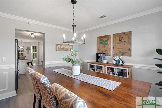 dining room featuring wood finished floors, visible vents, and ornamental molding