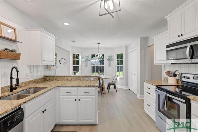kitchen featuring stainless steel appliances, light wood-style flooring, a textured ceiling, a sink, and white cabinetry