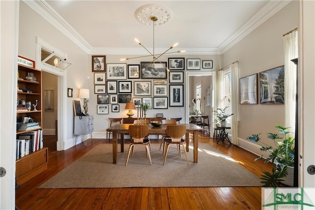 dining space featuring a notable chandelier, ornamental molding, and wood finished floors