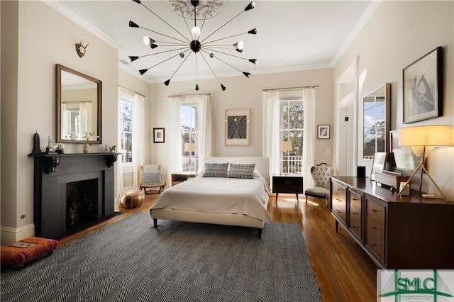 bedroom with dark wood finished floors, an inviting chandelier, access to outside, crown molding, and a fireplace