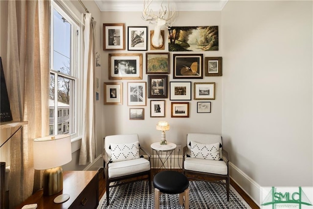 living area featuring baseboards, ornamental molding, wood finished floors, and a chandelier