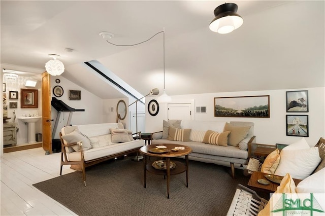 living area featuring lofted ceiling, light wood-style floors, and visible vents